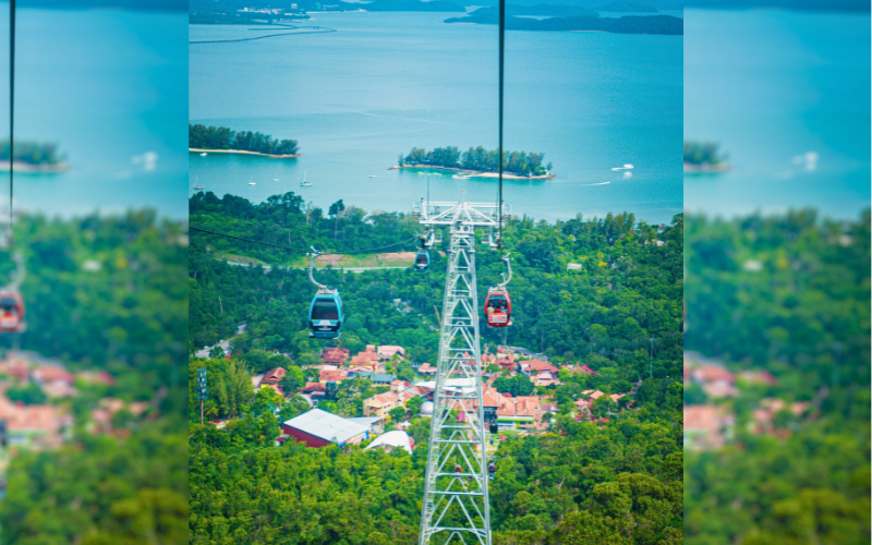 SkyCab cable car gliding high above tropical rainforests in Langkawi, Malaysia, with panoramic views of the Andaman Sea and nearby islands.