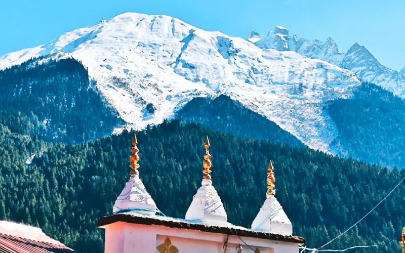 Snow-covered Himalayan mountains with pine forests and temple domes in the foreground, showcasing the natural beauty and cultural heritage of the Indian Himalayas.