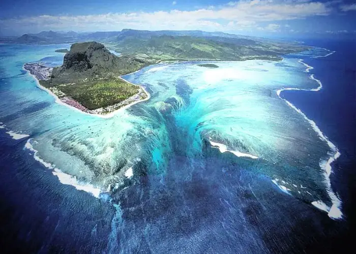 A breathtaking aerial image showing the hidden waterfall illusion in the Denmark Strait, where powerful ocean currents between Greenland and Iceland create a cascading effect beneath the surface — representing the world’s tallest underwater hidden waterfall.