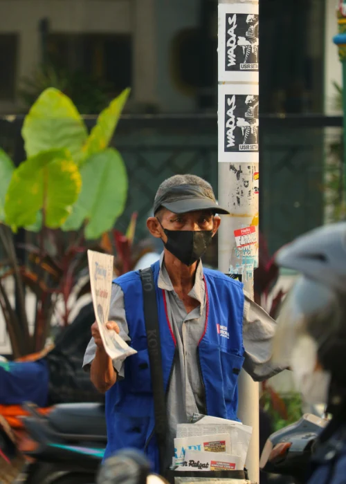 A street vendor wearing a mask and blue vest sells newspapers under intense sunlight, reflecting how people in Chinese cities adapt to the October 2025 heatwave.