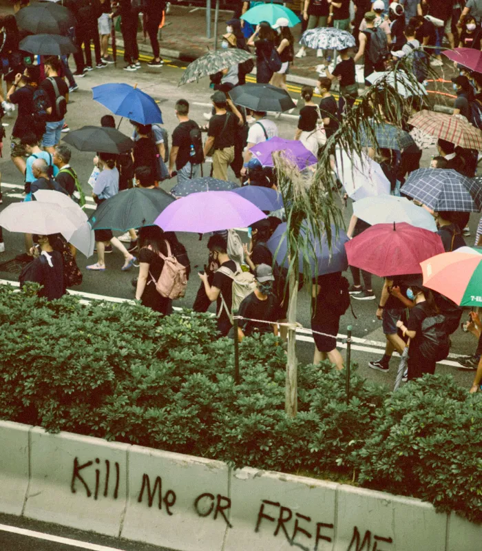 Crowd of people walking on a hot day using colorful umbrellas for shade, highlighting how communities cope with extreme October 2025 heat.