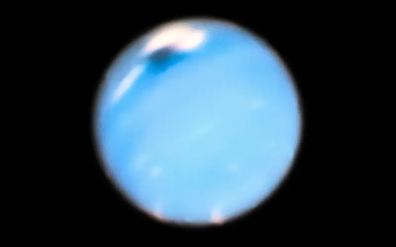 A detailed telescopic image of Uranus showing its pale blue-green atmosphere and faint cloud patterns against the blackness of space.