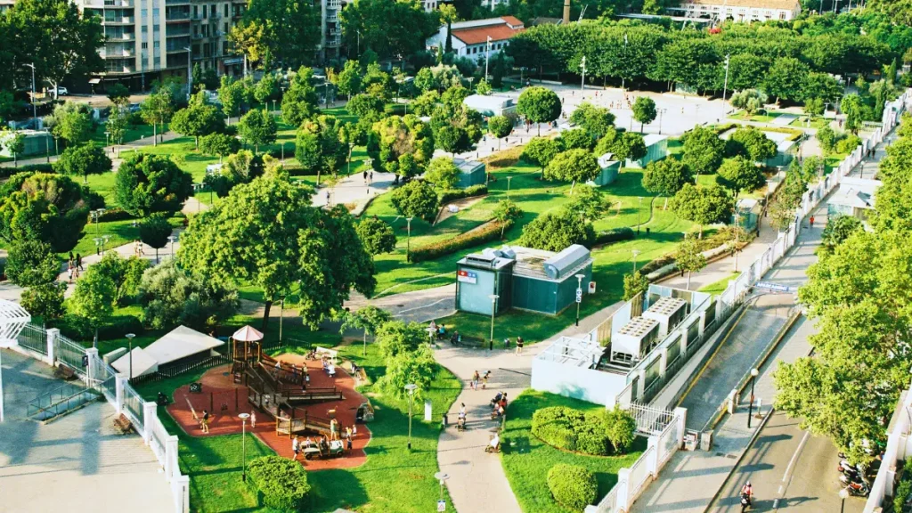 Aerial view of a modern sustainable city park with lush greenery, walking paths, playgrounds, and eco-friendly urban design promoting green living and sustainability.