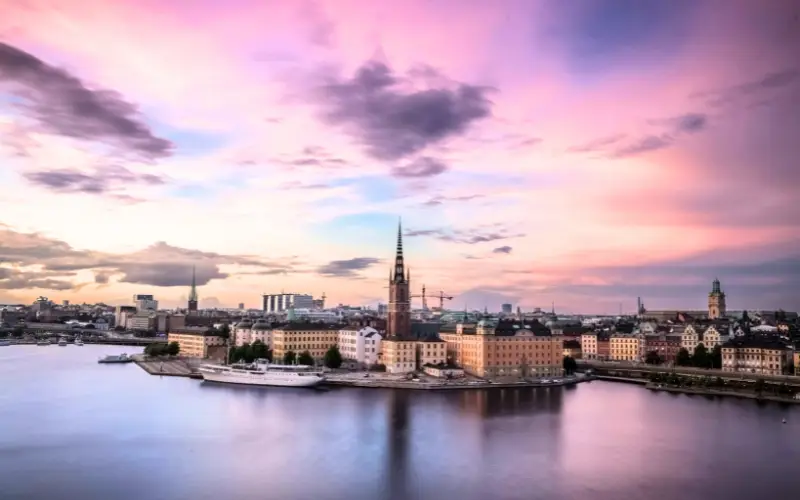 A breathtaking sunset view of Stockholm, Sweden, with historic buildings, calm waters, and pink skies highlighting the city’s harmony between nature and sustainable urban architecture.