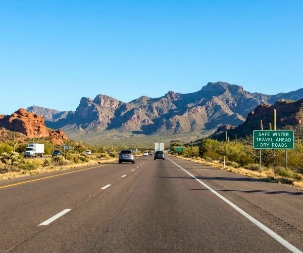A clear and dry desert highway in the Southwest showing low-snowfall travel conditions during winter.