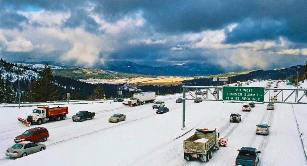 A U.S. highway showing snowy conditions on one side and clear dry travel lanes on the other, highlighting winter travel contrast.